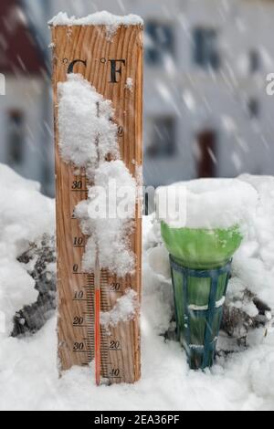 Regenmesser/Pluviometer für den Garten und Thermometer für den Außenbereich, die auf das Einfrieren hinweisen Temperatur von -6 Grad C 21 im Freien Schnee bei Schneefall im Winter Stockfoto