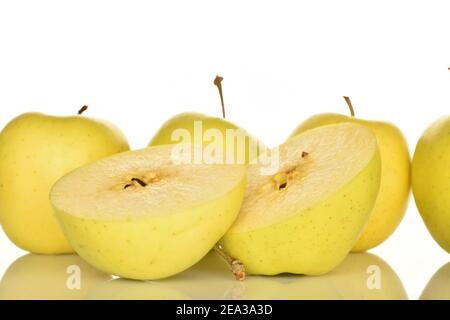 Im Vordergrund, im Fokus, zwei Hälften eines gelben reifen leckeren süßen aromatischen Äpfels auf weißem Hintergrund. Im Hintergrund vier ganze Äpfel. Stockfoto