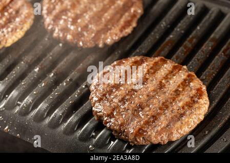 Frische Rinderschnitzel auf einem Grill. Kochen Sie einen Burger zu Hause. Leckeres und gesundes Essen Konzept Stockfoto