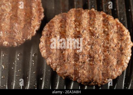 Frische Rinderschnitzel auf einem Grill. Kochen Sie einen Burger zu Hause. Leckeres und gesundes Essen Konzept. Nahaufnahme Stockfoto