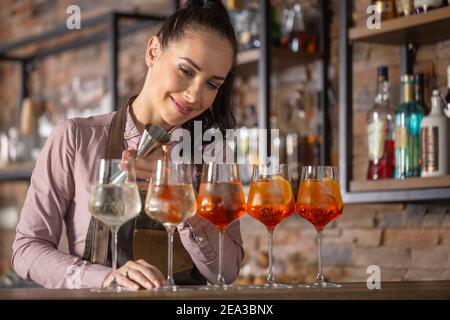 Happy Barkeeper macht aperol Spritz Cocktail an einer Bar zu fünf Gläsern. Stockfoto