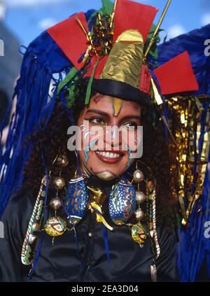 Großbritannien, England, London, Nottinghill Carnival, eine facepainted Afrokaribische Frau in Karneval Kopfschmuck, bemalte Ohrringe und königsblaue Jacke. Stockfoto