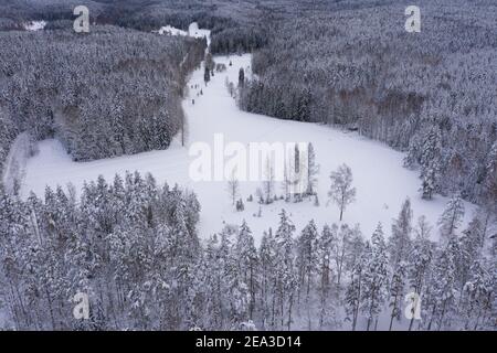 Landschaft mit Winterluft, verschneiten Wäldern und Seen. Foto von der Drohne. Skandinavische Natur, Finnland. Nuxio, ein wolkiger Tag, aß unter dem Schnee. Hochwertige Fotos Stockfoto