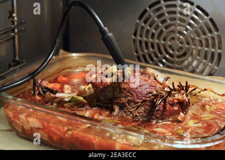 Nahaufnahme von köstlichem Roastbeef mit Rosma und Gemüse Im Ofen mit Thermometer Stockfoto