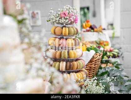 Horizontale schöne Macaron Kuchen Patisserie Multi Tier stehen voll Macarons alle Geschmacksrichtungen Farben echte Hochzeit mit Blumen und Rosen Rosa Schokolade Stockfoto