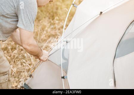 Ein Wanderer richtet ein Zelt auf dem Rasen in einem Wald in einem Nationalpark auf. Nahaufnahme auf Aluminium flexible Arcs-Sticks und Haken zum Anbringen der inneren Atemluft Stockfoto