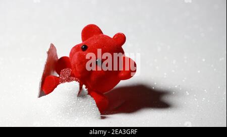 Roter Teddybär mit glänzendem roten Herz, das aus dem Hintergrund ausbricht, mit Platz auf der rechten Seite für Text. Stockfoto