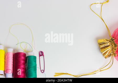 Gewinde in den Spulen und ein rosa Pin auf der Oberfläche des weißen Tisches flach. Reparatur und Nähen von Kleidung. Für Text platzieren. Stockfoto