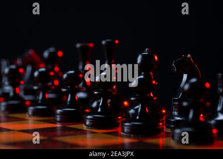 Schwarze Schachfiguren auf einem Schachbrett. Eine Armee von schwarzen Bauern auf dem Tisch. Stockfoto