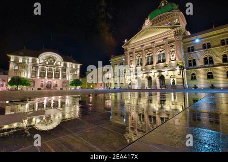 Bundespalastfassade in Bern, Schweiz und Schweizerische Nationalbank bei Nacht beleuchtet. Schweizer Parlamentsgebäude im Wasser reflektiert auf dem Bundesplatzn Stockfoto