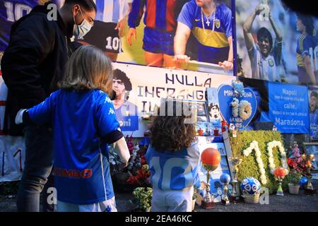 Kleine Mädchen Fans von Neapel, mit der offiziellen Uniform des Teams, mit ihrem Vater, bewundern die Bilder von Diego Armando Maradona, die spanischen Bezirke Stockfoto