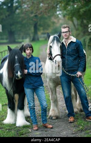 Junges Paar in Jeans Vorbereitung ihrer Pferde für einen Ausritt auf einem ländlichen Bauernhof. Stockfoto