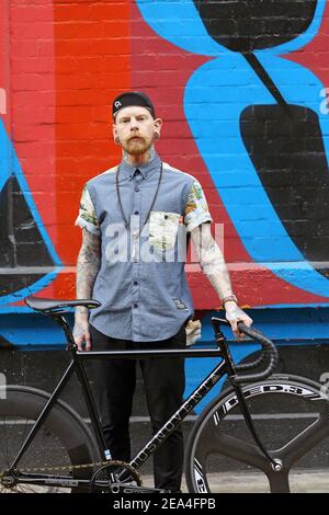 Junger Hipster Mann mit seinem Fahrrad vor Graffiti Wand Hintergrund. Stockfoto