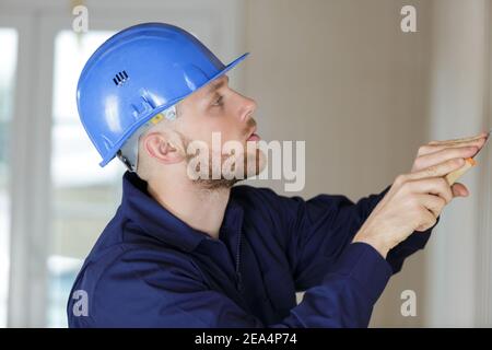 Handwerker kratzt alte Tapete von der Wand zu Hause Renovierung Stockfoto