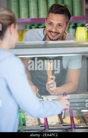 Porträt eines Kellners, der sich an der Theke im Salon auf Deckel stützt Stockfoto