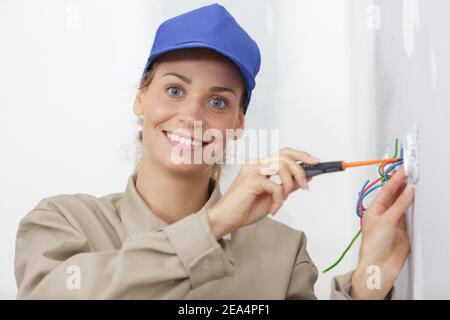 Elektrikerin mit Elektroschraubendreher zum Testen der Steckdose Stockfoto