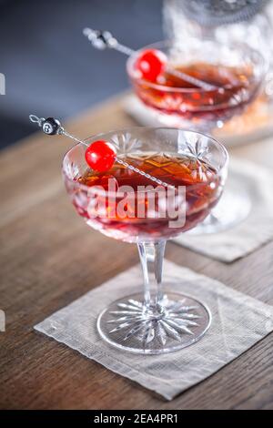 Manhattan klassischer Cocktail als Kurzgetränk-Aperitif mit Whisky, Wermut, angostura aromatischer Bitter und Kirsche garnieren. Stockfoto