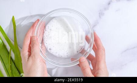 Aloe Vera hausgemachtes Gesicht und Körper Peeling Rezept. Aloe Vera Gel Nahaufnahme in einer Glasschale auf Marmor Hintergrund Stockfoto