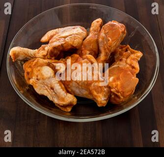 Hähnchenbüffelflügel roh in Schüssel mit würziger Sauce auf einem isolierten Hintergrund gewürzt. Stockfoto