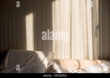 Sonnenstrahl fällt auf das Bett. Die Sonne strahlt am Morgen durch das Fenster. Neuer Tag mit warmem Sonnenlicht Flare. Stockfoto