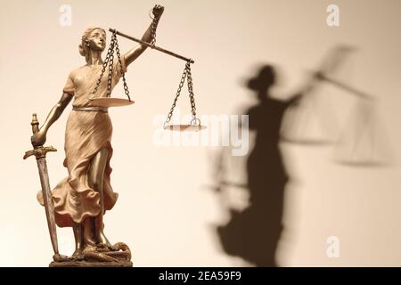 Gerechtigkeit (griechisch: themis, lateinisch: justitia) mit verbundenen Augen mit Waage, Schwert und Geld auf einer Skala. Stockfoto