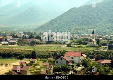 Typisches kroatisches Dorf Herzegowina mit einer katholischen Kirche am Fluss Neretva in einem Tal in der Nähe der Stadt Mostar (Bosnien und Herzegowina). Nere Stockfoto