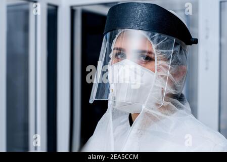 Porträt einer weiblichen Sanitäter in einem Schutzanzug und Eine Plastikmaske auf ihrem Gesicht in einem Labor Stockfoto