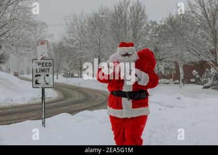 Schnee Weihnachtsmann zu Fuß entlang der Straße trägt eine große Beutel mit Geschenken auf Bäumen mit Schnee bedeckt Stockfoto