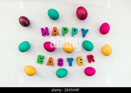 Farbige Ostereier und Frohe Ostern Inschrift auf dem Tisch Stockfoto