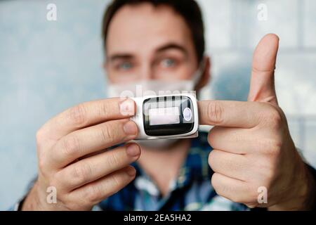 Pulsoximeter am Finger ist eine gute Möglichkeit, den Sauerstoffgehalt des Blutes im Falle einer Virusinfektion der Lunge zu testen. Hoher Sättigungsindex, gesunder junger Mann. i Stockfoto