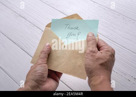Mann öffnen und schauen Sie sich Dankeskarte oder Notiz in einem braunen Umschlag. Nahaufnahme. Stockfoto