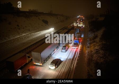 Dresden, Deutschland. Februar 2021, 08th. Auf der verschneiten Autobahn 4 bei Dresden stecken Autos und Lastwagen im frühen Schneefall in einem Stau fest, während ein Mann neben seinem Auto steht. Quelle: Robert Michael/dpa-Zentralbild/dpa/Alamy Live News Stockfoto