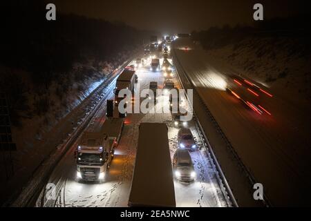 Dresden, Deutschland. Februar 2021, 08th. Auf der verschneiten Autobahn 4 bei Dresden stecken Autos und Lastwagen im frühen Schneefall in einem Stau fest, während ein Mann neben seinem Auto steht. Quelle: Robert Michael/dpa-Zentralbild/dpa/Alamy Live News Stockfoto
