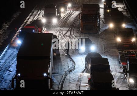 Dresden, Deutschland. Februar 2021, 08th. Auf der verschneiten Autobahn 4 bei Dresden stecken Autos und Lastwagen im frühen Schneefall in einem Stau fest, während ein Mann die Straße zwischen den Fahrzeugen entlang läuft. Quelle: Robert Michael/dpa-Zentralbild/dpa/Alamy Live News Stockfoto