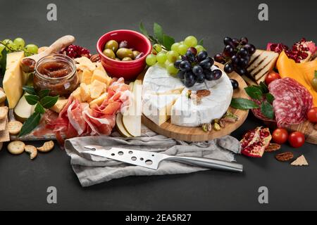 Vorspeisentisch. Käse, Fuits und Fleischtafel auf dunklem Hintergrund Stockfoto