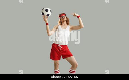 Lustiger Nerdy Mann in Brille und Sportswear hält Fußball Und stolz auf sich selbst zeigend Stockfoto