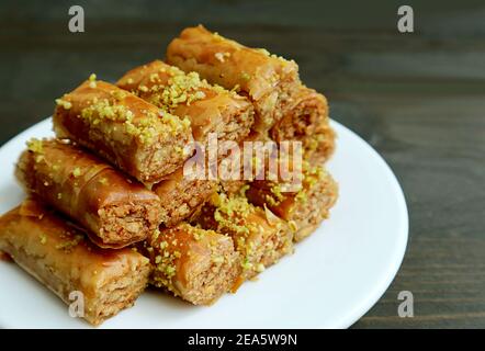 Teller mit knusprigen und süßen Baklava-Gebäck mit Pistazien-Nüssen Auf schwarzem Holzhintergrund Stockfoto