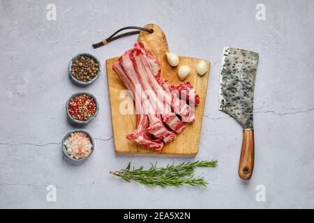 Blick von oben auf rohe frische Hirsch Rippen mit Gewürzen und Kraut über Beton Hintergrund Stockfoto