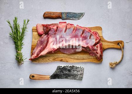 Blick von oben auf rohe frische Hirsch Rippen mit Gewürzen und Kraut über Beton Hintergrund Stockfoto