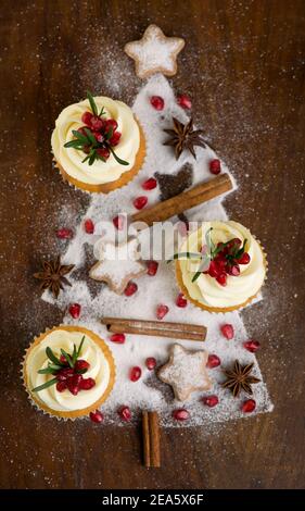 Weihnachts-Cupcakes mit Vanillefrosting, Preiselbeeren und Rosmarin auf Holzhintergrund Stockfoto