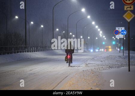 Dresden, Deutschland. Februar 2021, 08th. Ein Mann fährt bei Schneefall mit dem Fahrrad entlang einer verschneiten Straße in der Innenstadt. Quelle: Robert Michael/dpa-Zentralbild/dpa/Alamy Live News Stockfoto