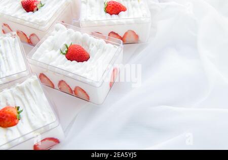 Erdbeer-Shortcake in Kunststoffbox auf mit Stoffhintergrund und Kopierraum, Minimal-Kuchen und Bäckereikonzept Stockfoto