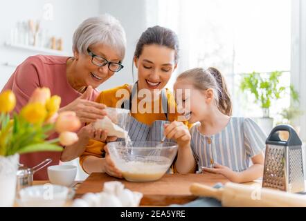 Glücklich liebende Familie bereiten Bäckerei zusammen. Oma, Mama und Kind kochen Kekse und haben Spaß in der Küche. Stockfoto