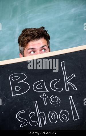 Sind Sie bereit, zu studieren. Lehrer oder Schulleiter begrüßt Inschrift zurück in die Schule. Erzieher versteckt sich hinter Tafel. Lehrer heraus spähen Tafel. Schuljahr vorbereiten. Bildungschancen. Stockfoto