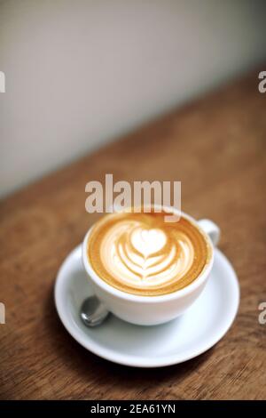 Cappuccino oder Latte Art Kaffee aus Milch auf dem Holz Tisch im Café Stockfoto