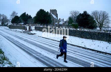 Ein Mann geht zur Arbeit entlang einer mit Schnee bedeckten Straße in Great Chart, nahe Ashford in Kent, nachdem das Met Office eine schwere bernsteinfarbene Schneewarnung für London und Südostengland herausgegeben hat, wo starker Schnee wahrscheinlich lange Verzögerungen auf Straßen und mit Bahn- und Flugreisen verursachen wird. Bilddatum: Montag, 8. Februar 2021. Stockfoto