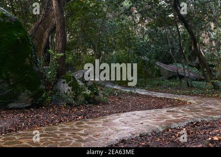 Mit Naturstein gepflasterte Wege zwischen Naturfelsen in anсient Landschaftsgarten Stockfoto