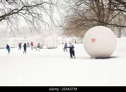 07. Februar 2021, Nordrhein-Westfalen, Münster: Zwischen den Skulpturen "Riesenbälle" des Künstlers Claes Oldenburg am Aasee genießen die Menschen den Schneefall. Bis zu 30 Zentimeter Schnee waren in Ostwestfalen und im Münsterland in der Nacht auf Sonntag innerhalb weniger Stunden gefallen. Foto: Ute Friederike Schernau/dpa Stockfoto