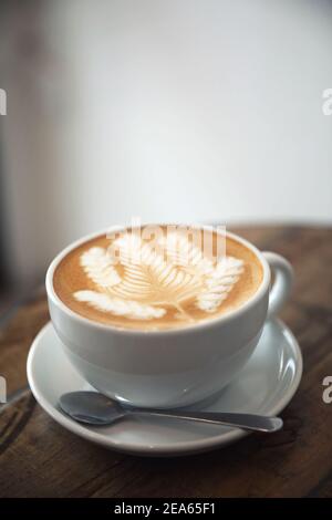 Cappuccino oder Latte Art Kaffee aus Milch auf dem Holz Tisch im Café Stockfoto