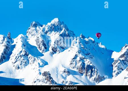 Farbenfroher Heißluftballon über hohen Berggipfeln der französischen Alpen An sonnigen Tag Stockfoto